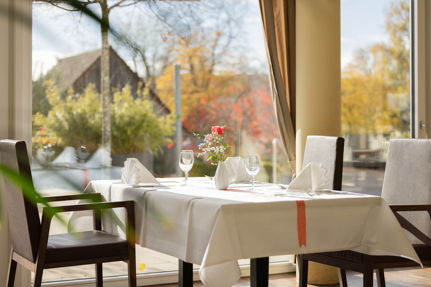 Stilvoll gedeckter Tisch im Restaurant Schönbühl mit Ausblick auf die grüne Umgebung.