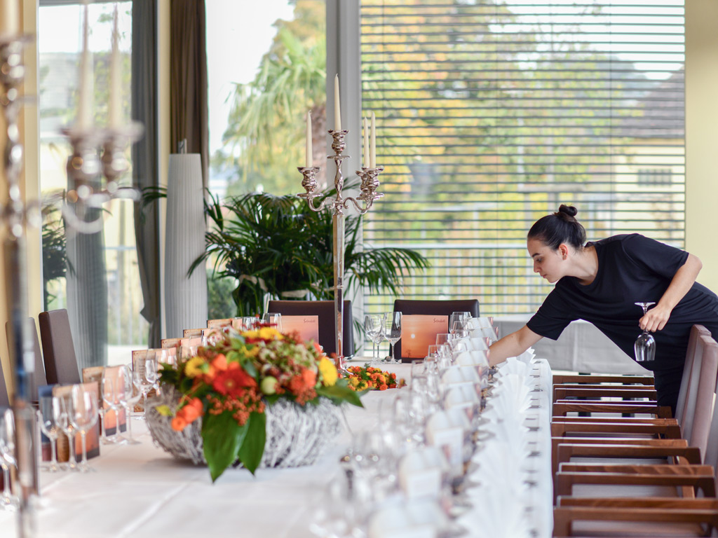 Service-Mitarbeiterin bereitet im Restaurant Schönbühl eine festlich gedeckte Tafel für Gäste vor.
